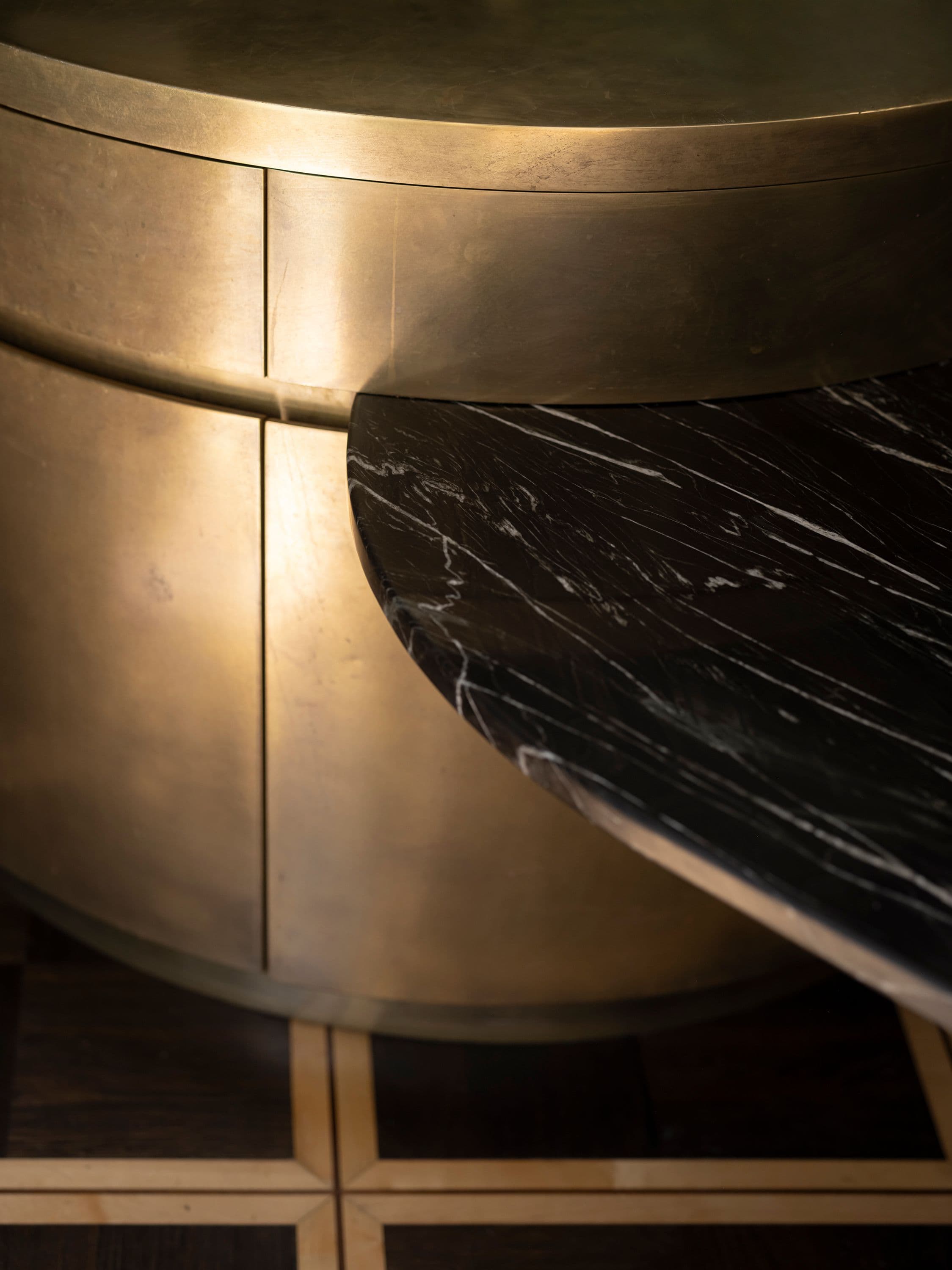 Detailaufnahme der ovalen Bronzeküche mit schwarzer Marmorarbeitsplatte und Messingintarsien im Tafelparkett in einem Privathaus, Innenarchitektur Susanne Philippson