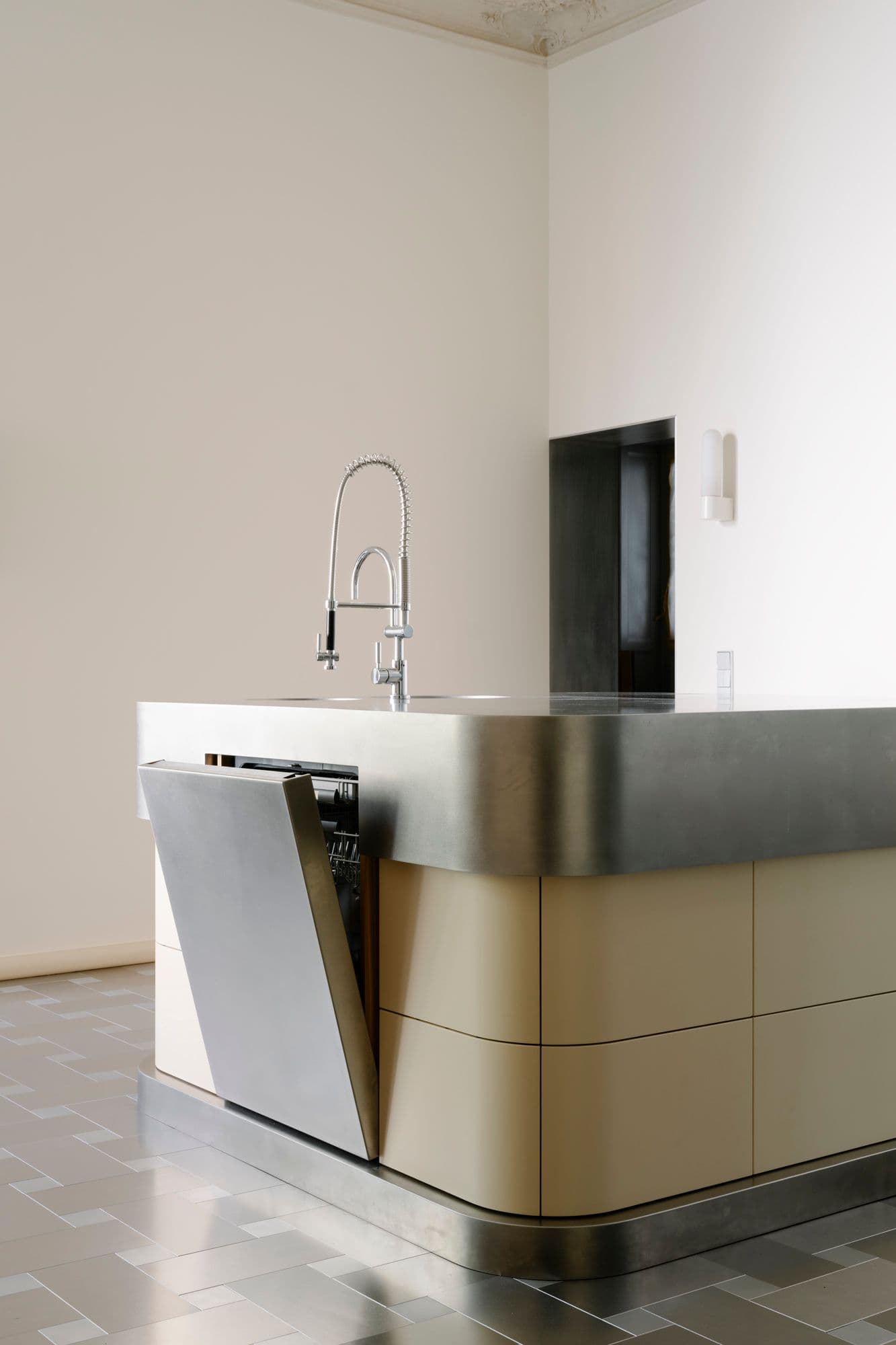 Maßgefertigte Edelstahlkücheninsel einer Berliner Altbauwohnung mit geöffneter Schublade mit Holzeinsatz, zweifarbigem Fliesenboden im Schachbrettmuster und geschlossener sowie geöffneter Spülmaschine, Innenarchitektur Susanne Philippson