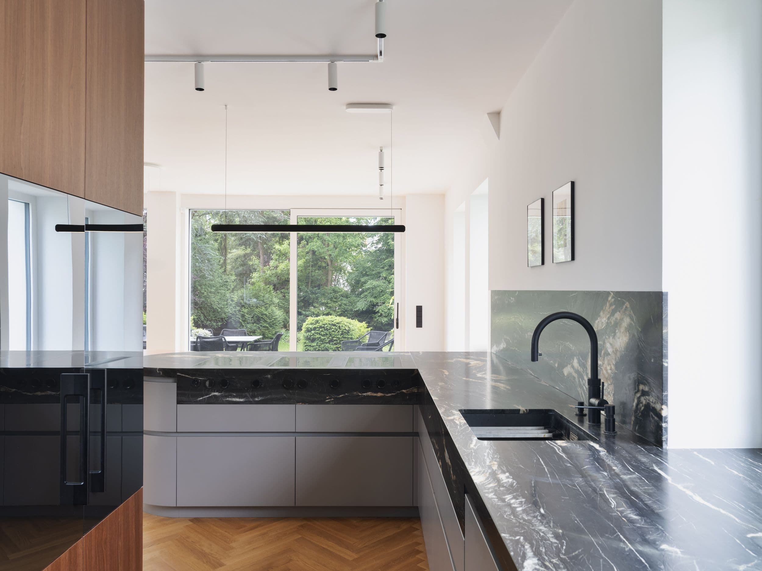 Maßgefertigte Küche mit schwarzem Marmor, gerundeter Kücheninsel und Holzeinbauten in einer Berliner Wohnungssanierung, Innenarchitektur Susanne Philippson