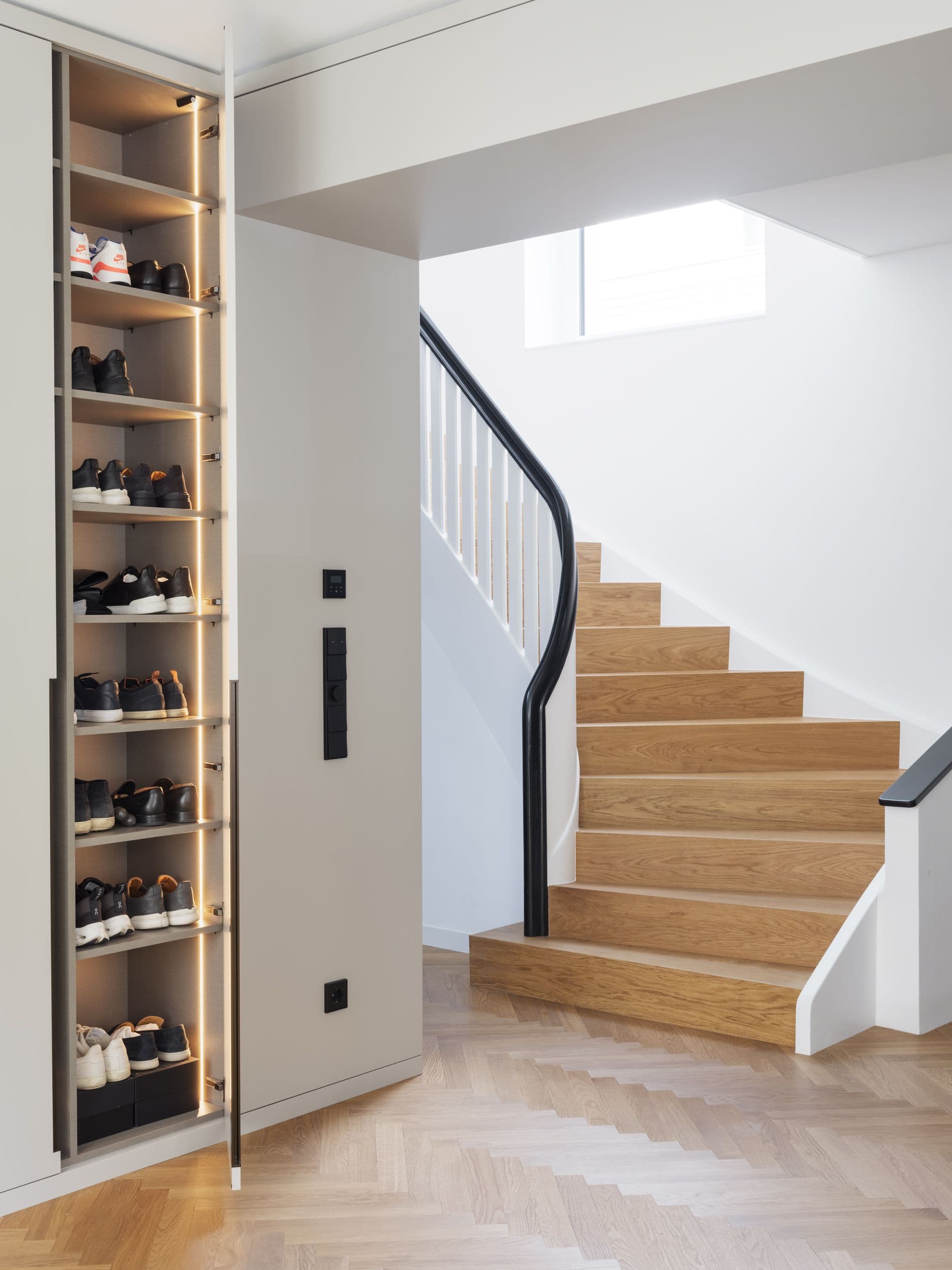 Maßgefertigte Einbauschränke, beleuchteter Schuhschrank und Treppenhaus mit geschwungenem Geländer – individueller Innenausbau in einer Berliner Sanierung, Innenarchitektur Susanne Philippson