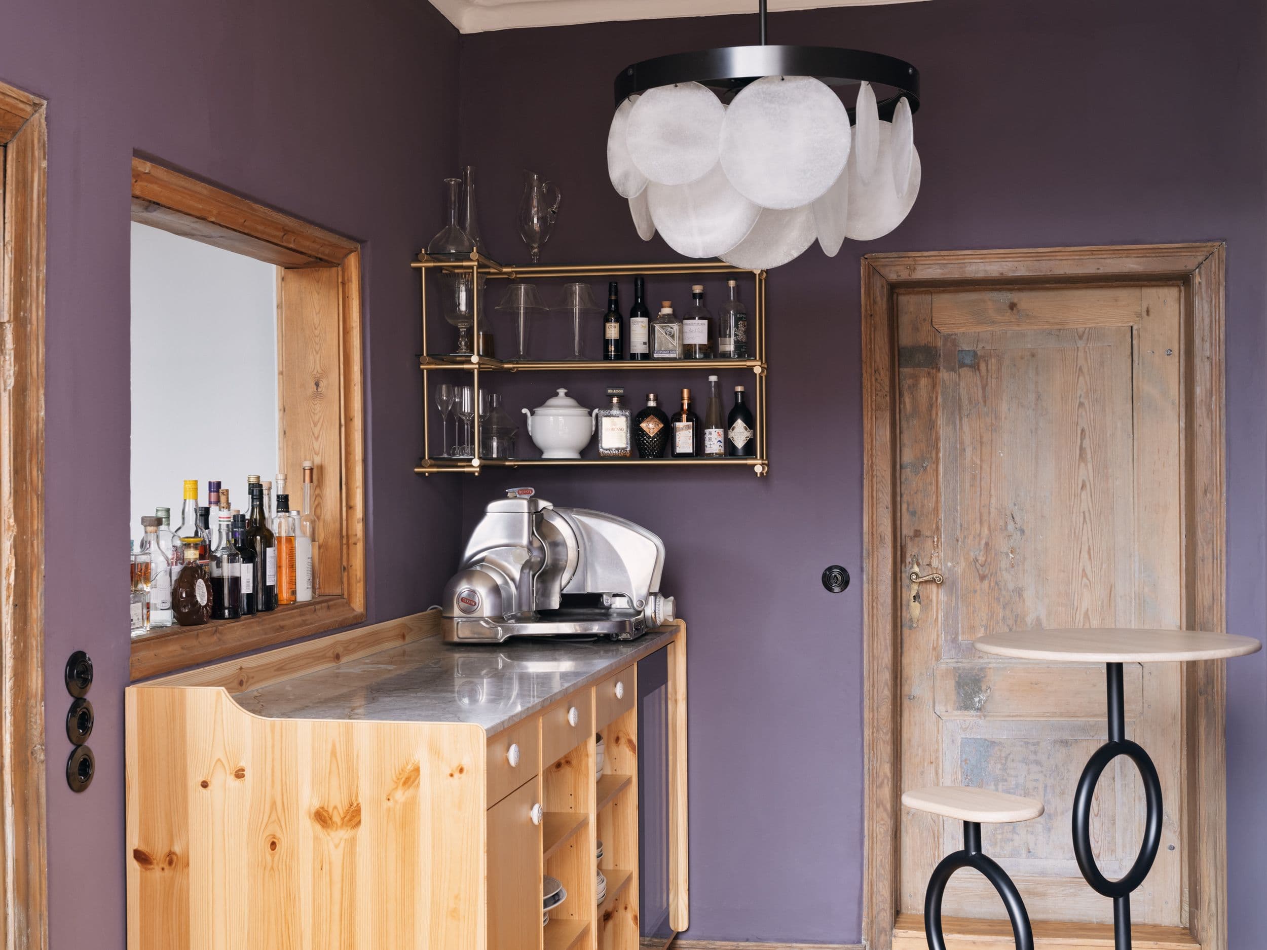Barraum der B21 in Potsdam mit violetten Wänden, maßgefertigtem Kiefernholztresen, Messingbarthregal und skulpturaler Pendelleuchte, Innenarchitektur Susanne Philippson
