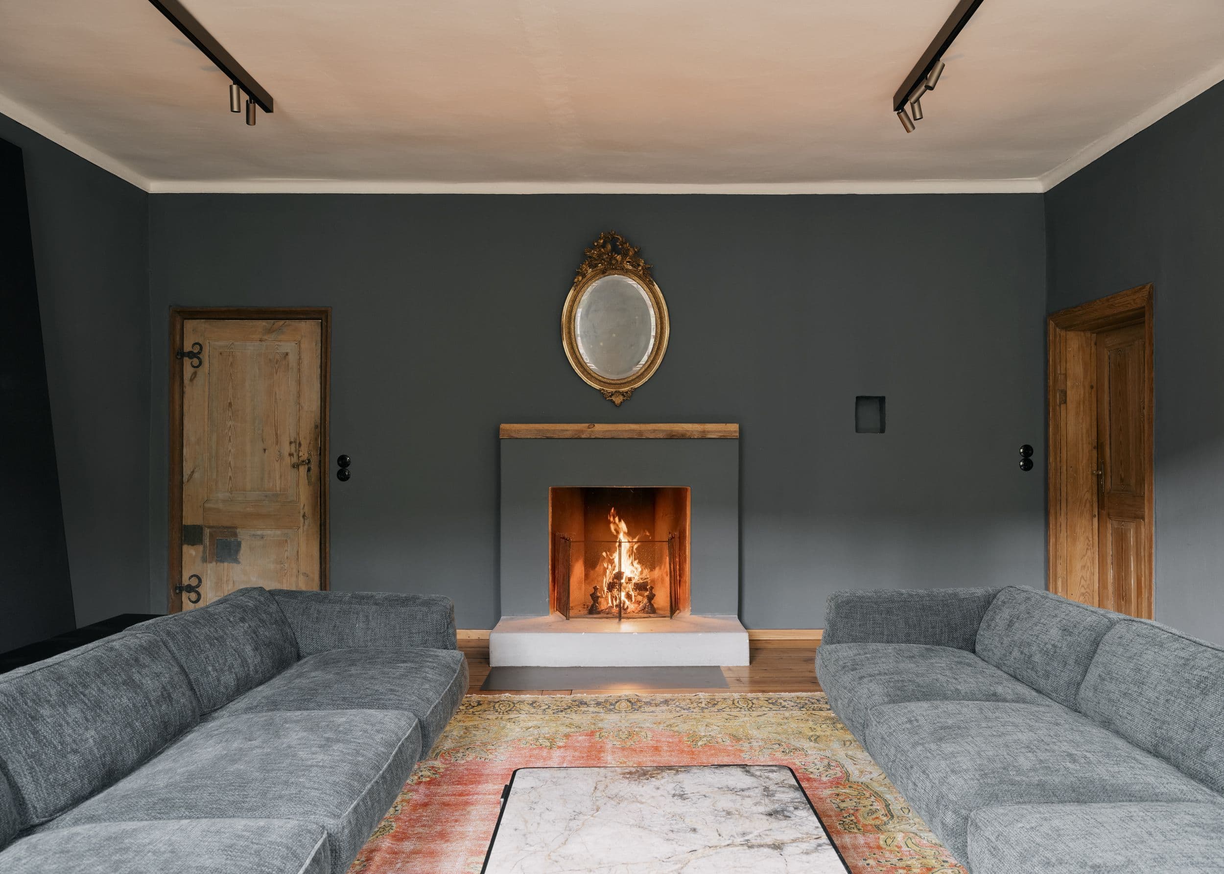 Wohnzimmer der B21 im holländischen Viertel Potsdam mit offenem Kamin, grauem Ecksofa, großformatigem Kunstwerk und historischen Kieferndielen, Innenarchitektur Susanne Philippson