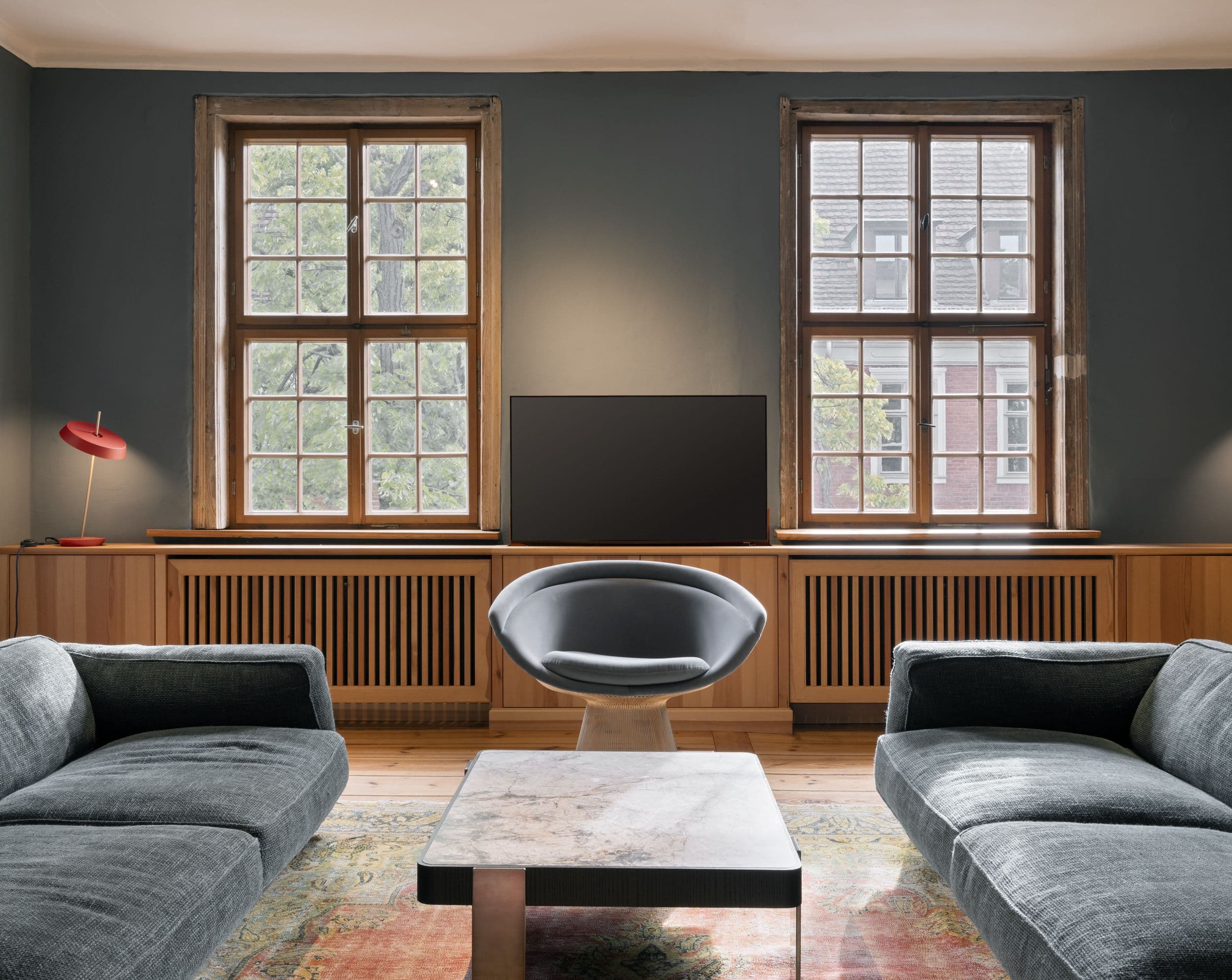 Wohnzimmer der B21 im holländischen Viertel Potsdam mit offenem Kamin, grauem Ecksofa, großformatigem Kunstwerk und historischen Kieferndielen, Innenarchitektur Susanne Philippson