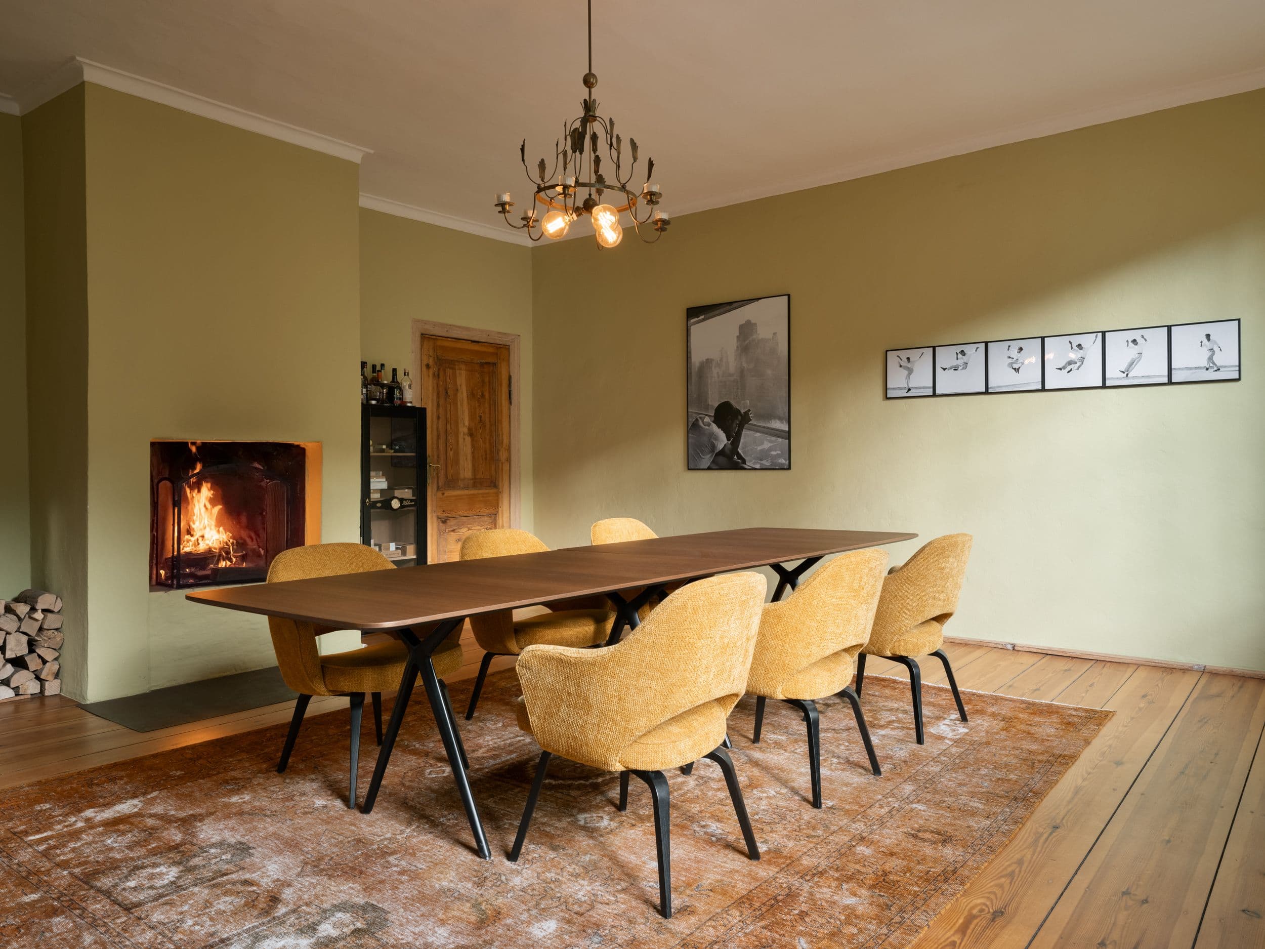Esszimmer der B21 im holländischen Viertel Potsdam mit großem Nussbaum-Esstisch, senfgelben Polsterstühlen, offenem Kamin und olivgrünen Wänden, Innenarchitektur Susanne Philippson
