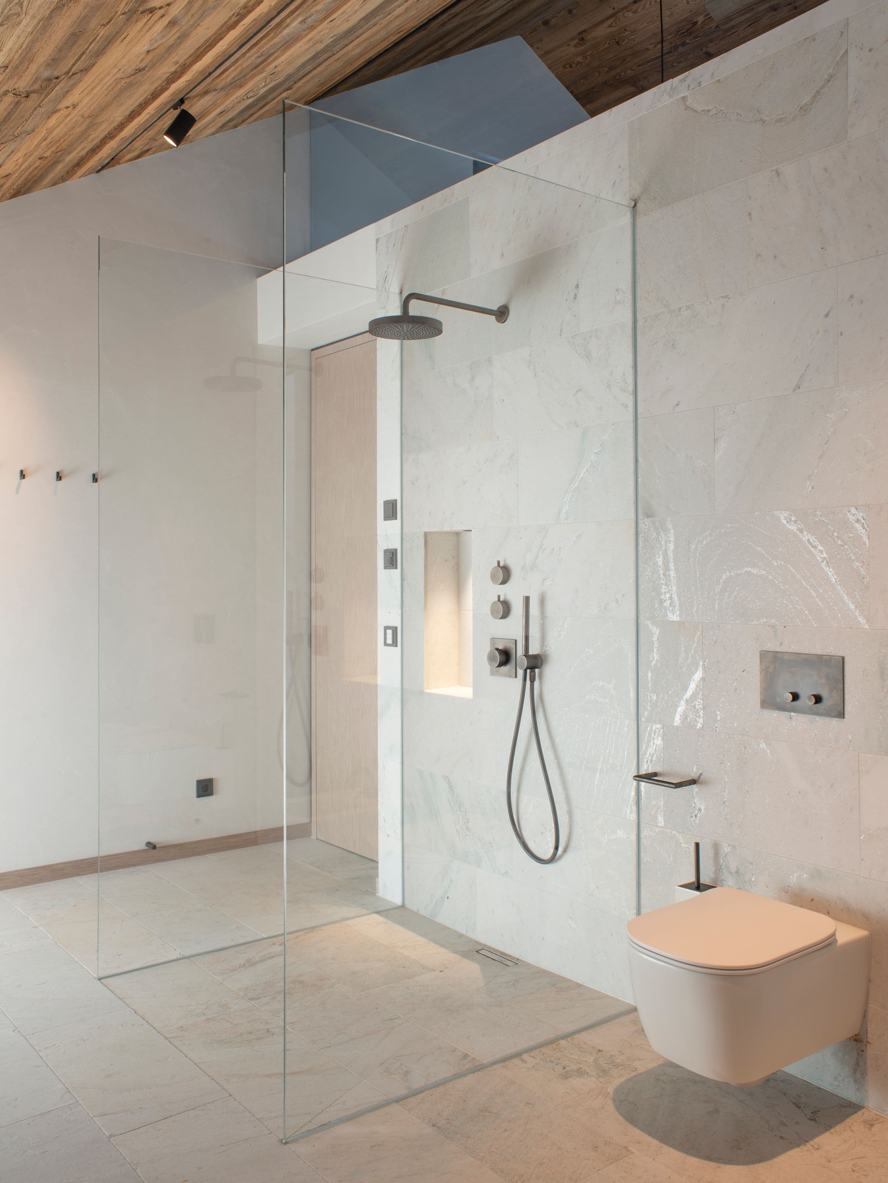 Badezimmer mit Silberquarzit-Naturstein, Doppelwaschtisch aus Holz, Glasdusche und Altholzdecke in einem Privathaus in Tirol, Innenarchitektur Susanne Philippson