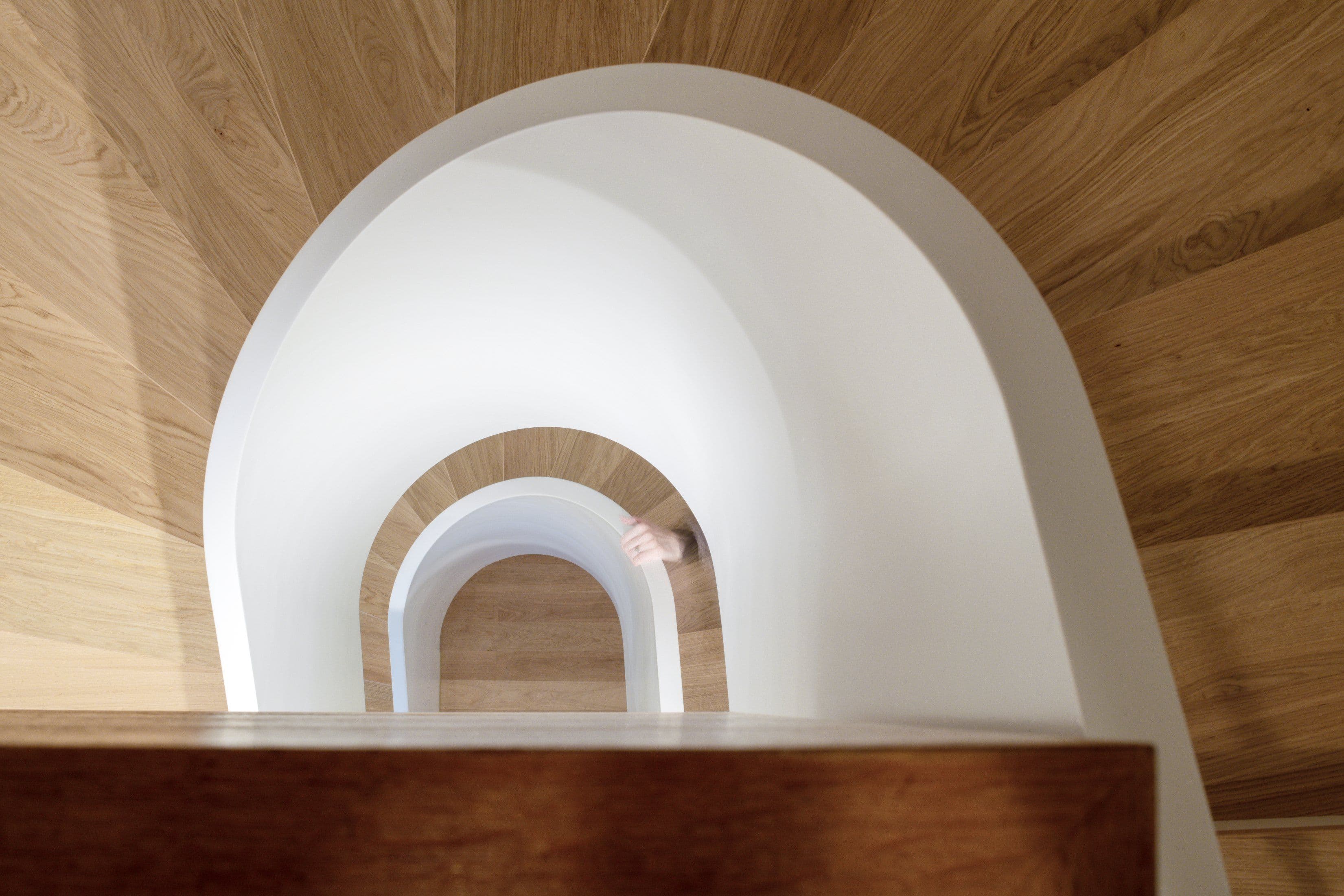 Detailaufnahme des geschwungenen Treppenhauses mit sich wiederholenden weißen Rundbögen und Eichenholzverkleidung in einer Privatwohnung, Innenarchitektur Susanne Philippson
