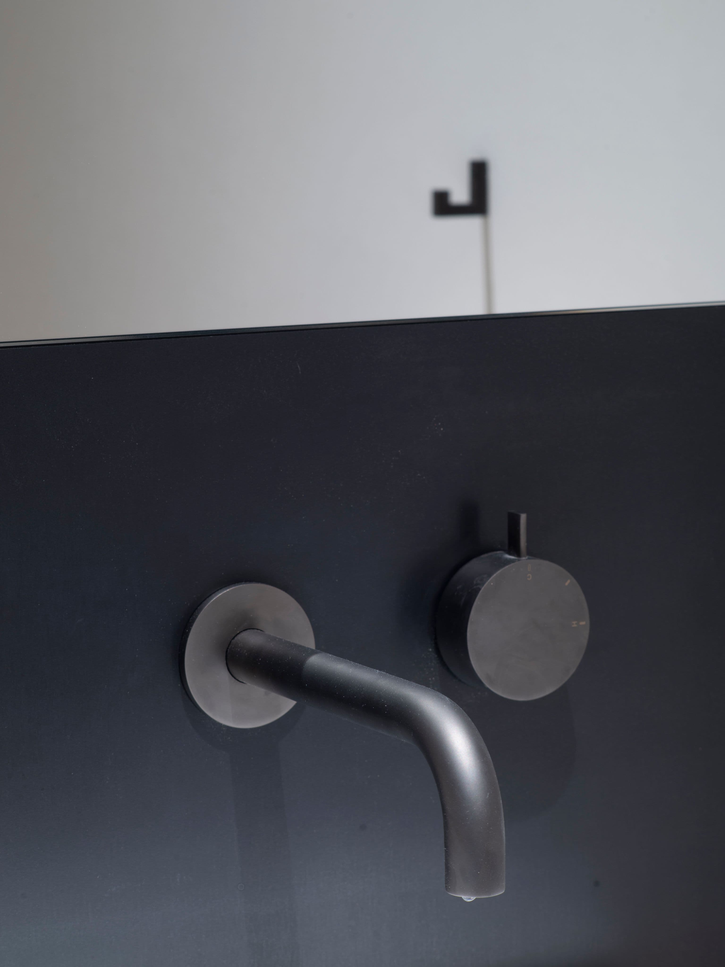 Gäste-WC mit aufgesetztem Aufsatzwaschbecken, schmalem Spiegel und Wandarmatur auf Schwarzstahlrückwand in einem Privathaus in Tirol, Innenarchitektur Susanne Philippson