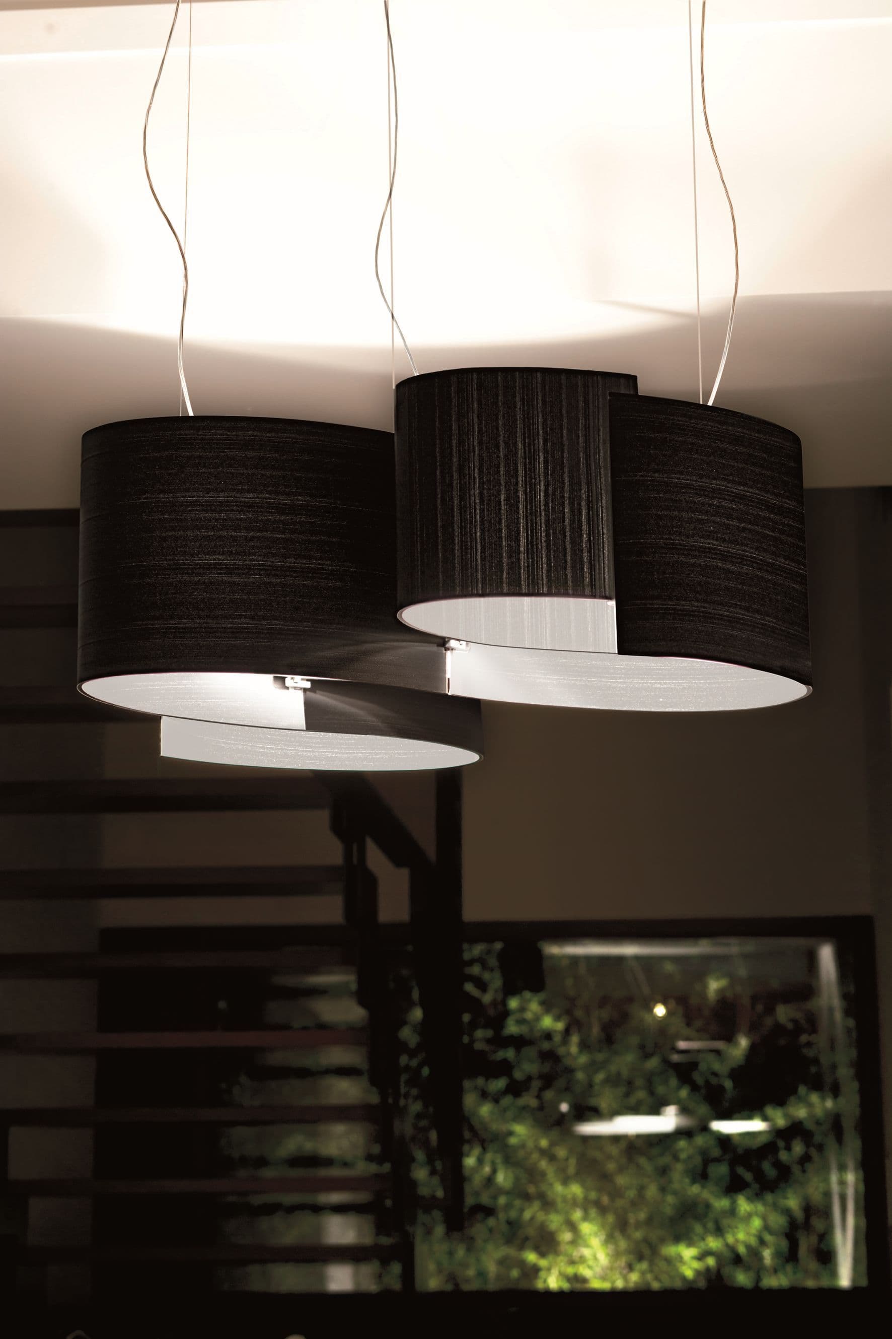 Joiin Stehleuchte von Pallucco in Schwarz mit kombinierten gebogenen Schirmflächen in Dachgeschossambiente mit Satteldachgebälk und Eames-Sesseln, Leuchtendesign Susanne Philippson