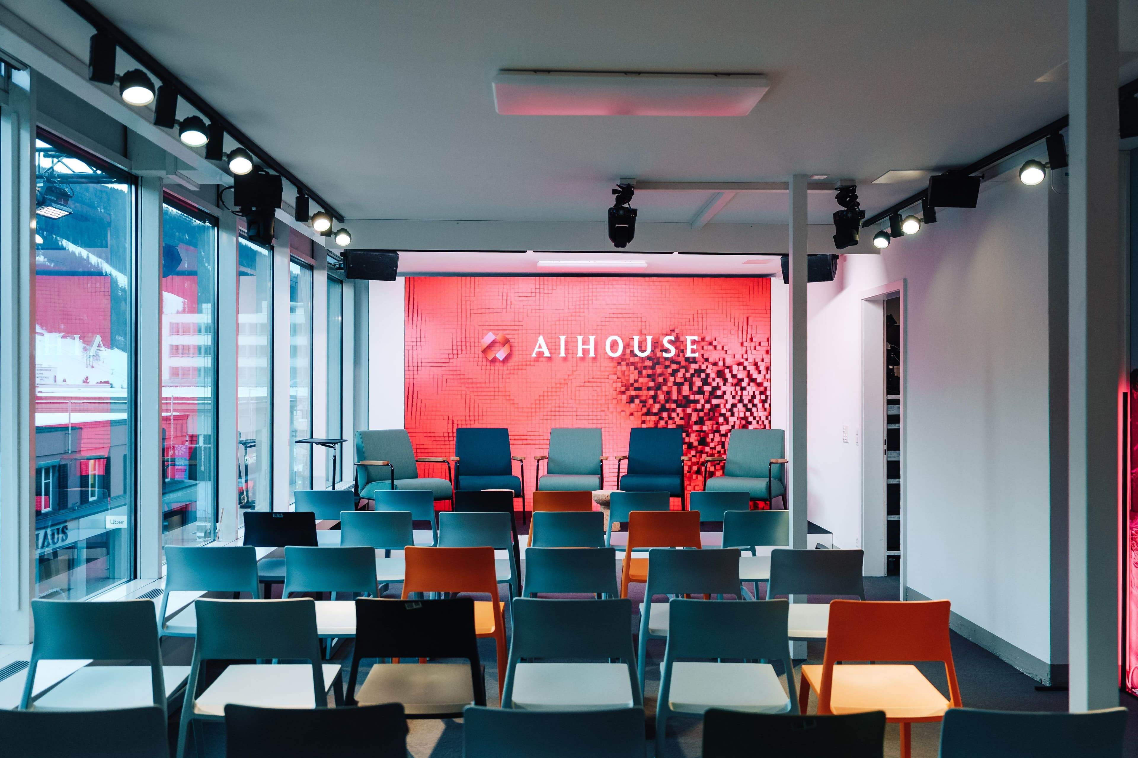 Panelraum und Speaker-Lounge des AI House Davos mit gebrandetem Pixelmuster-Hintergrund, Bestuhlung und Panoramafenster zur Promenade, Innenarchitektur Susanne Philippson