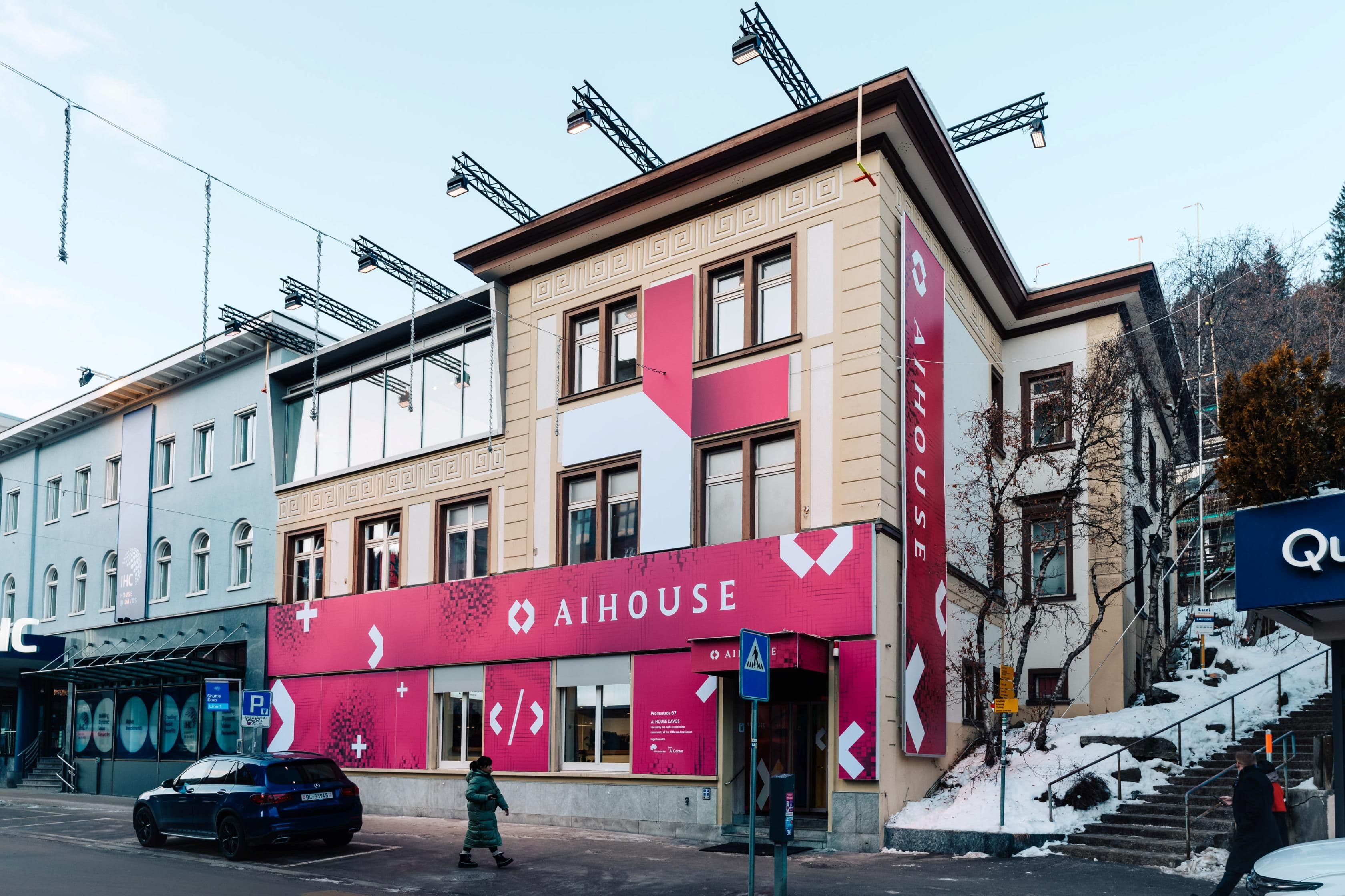 Außenansicht des AI House Davos an der Promenade mit großflächiger roter Markenbeschriftung und Menschenmenge vor dem Eingang, Innenarchitektur Susanne Philippson