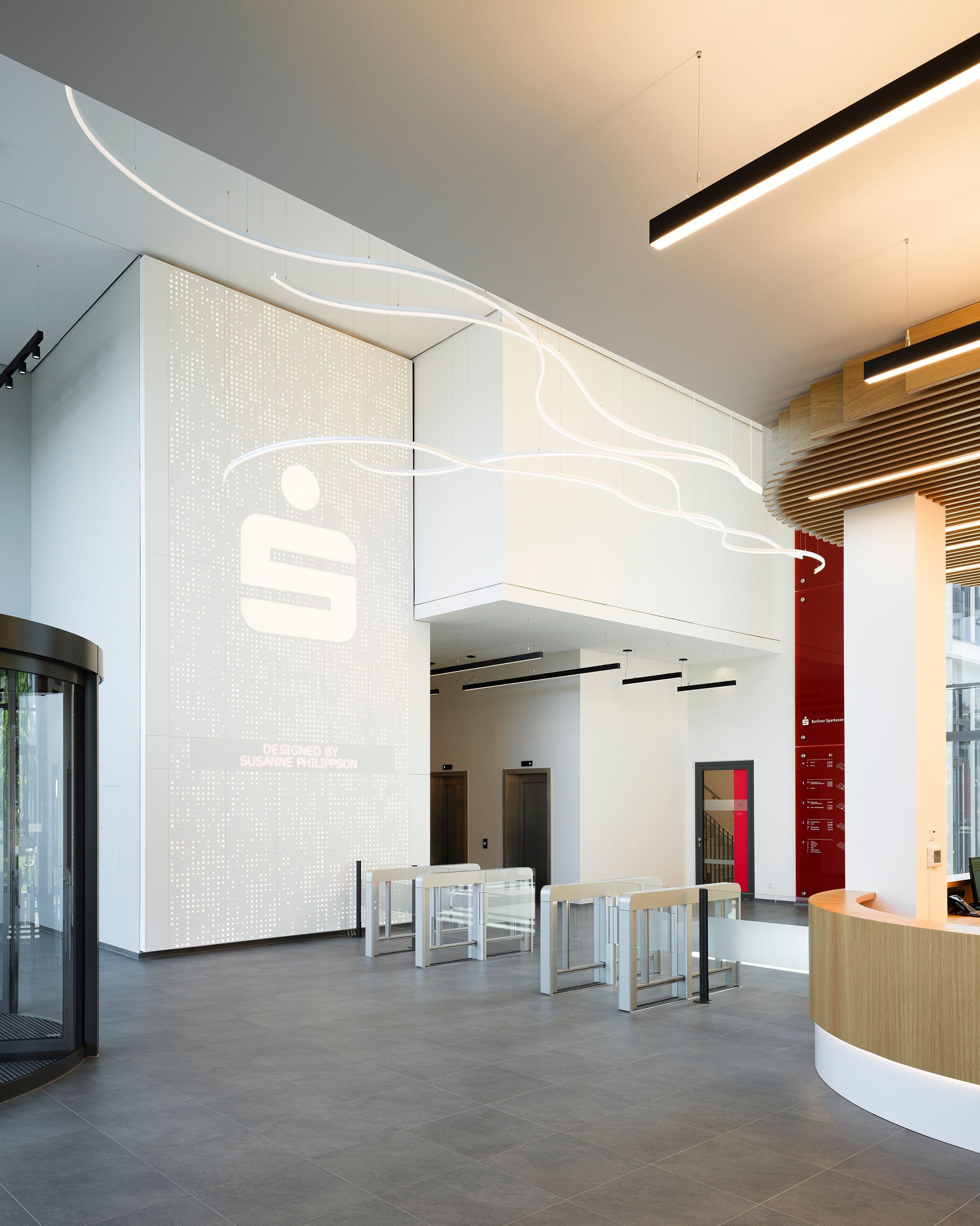 Foyer der Berliner Sparkasse mit geschwungener Lichtlinie an der Decke und LED-Pixelwand im Hintergrund, Lichtplanung Susanne Philippson