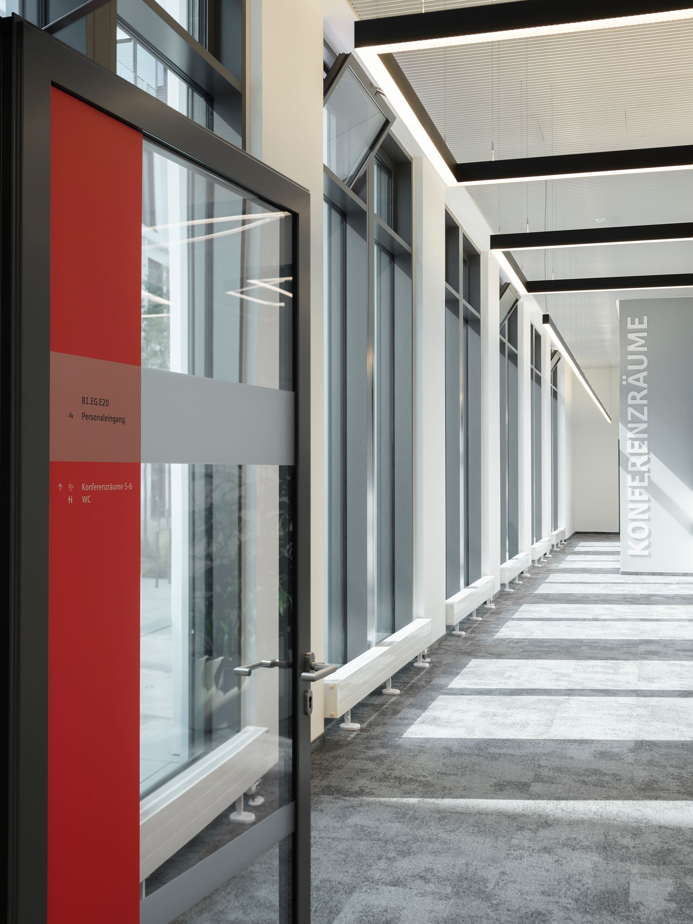 Lichter Flurbereich mit roter Orientierungsstele, Wegweisern zu Konferenzräumen und großformatigem Wandschriftzug im Berliner Sparkasse Hauptsitz, Signaletik Susanne Philippson