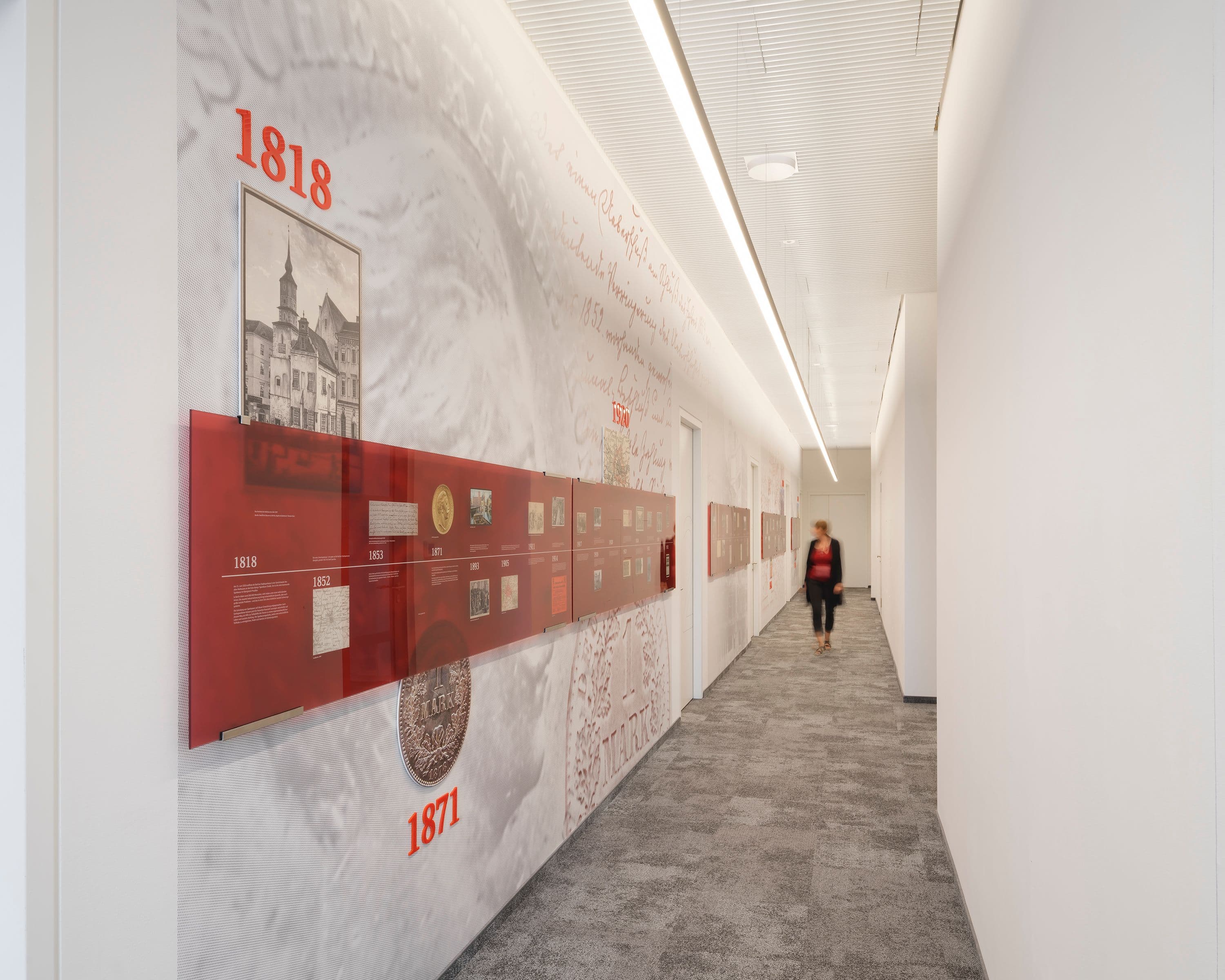 Historischer Zeitstrahl der Berliner Sparkasse seit 1818 – Wandgestaltung mit Archivmotiven, Jahreszahlen und roten Glaselementen entlang eines Büroflurs, Branding Susanne Philippson