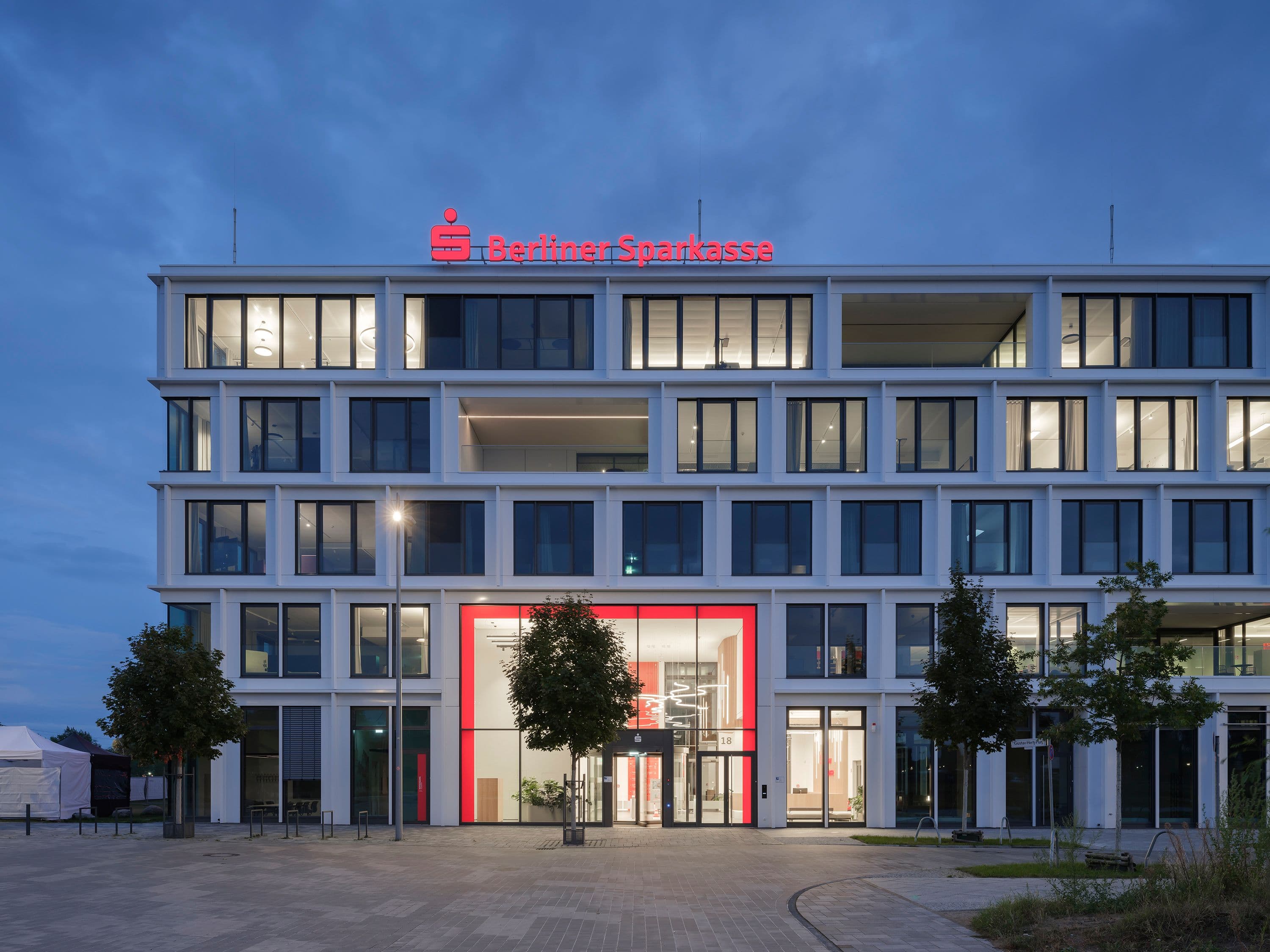 Square-One-Headquarter der Berliner Sparkasse bei Nacht – rot leuchtende Lichtbrücke zwischen den Gebäudeteilen als weithin sichtbares Stadtlandmark, Lichtplanung Susanne Philippson