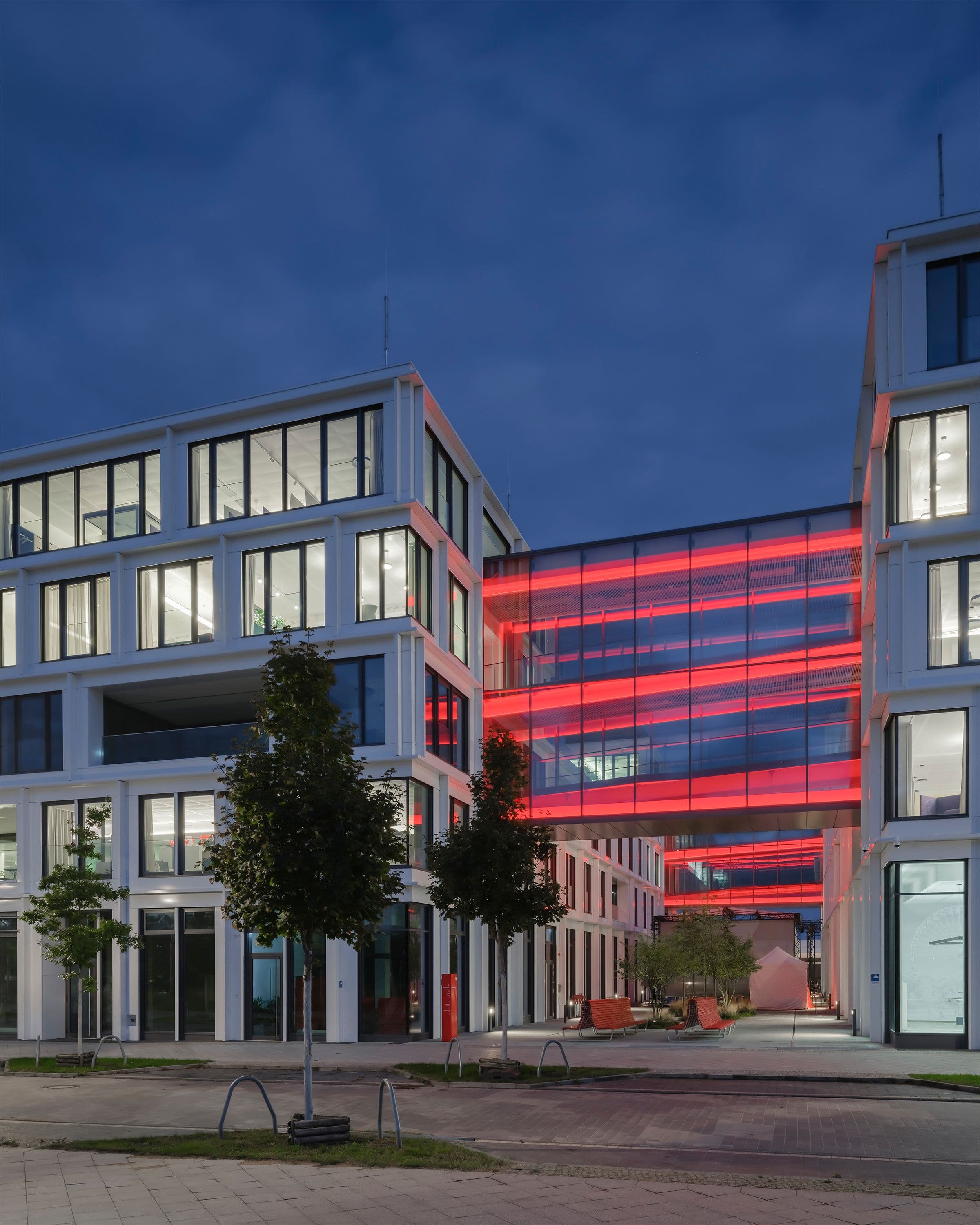 Square-One-Headquarter der Berliner Sparkasse bei Nacht – rot leuchtende Lichtbrücke zwischen den Gebäudeteilen als weithin sichtbares Stadtlandmark, Lichtplanung Susanne Philippson