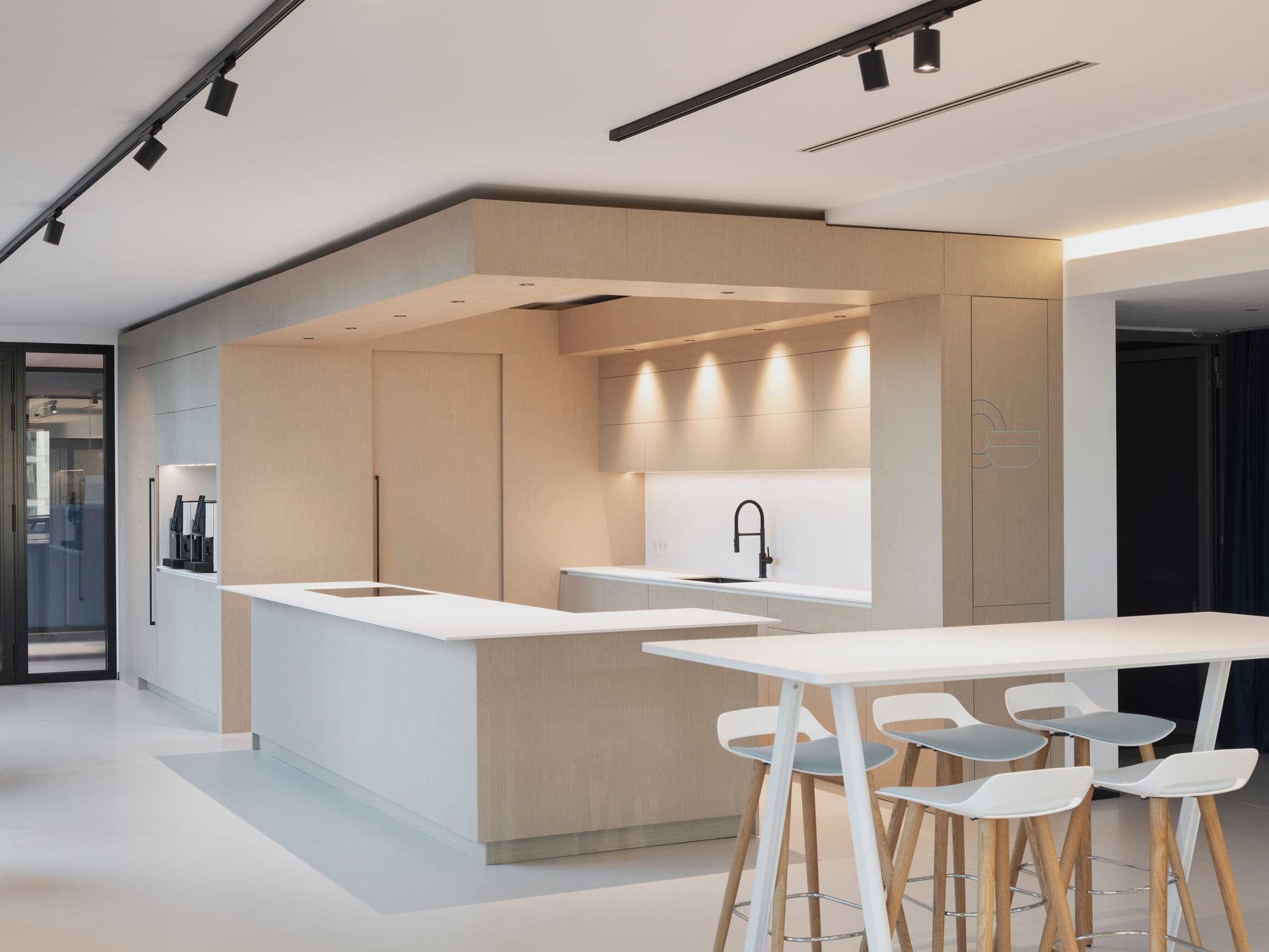 Helle Teeküche mit Holzfronten, integrierter Deckenverkleidung, Kücheninsel und Barhockern von Wilkhahn im TÜV Verband Berlin