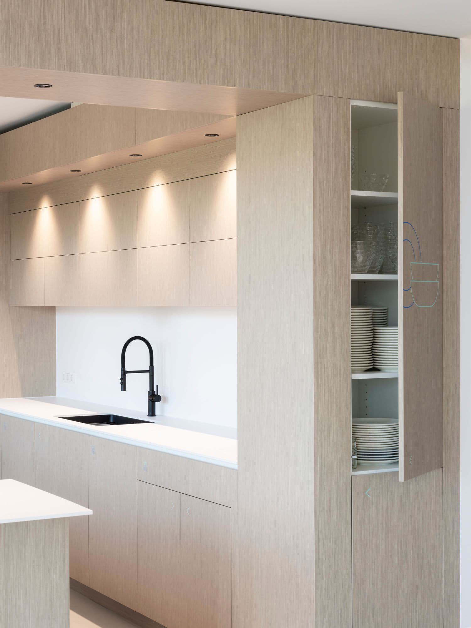 Detailansicht der Teeküche mit maßgefertigten Holzfronten, schwarzem Armaturendesign und offenem Geschirrschrank im TÜV Verband Berlin
