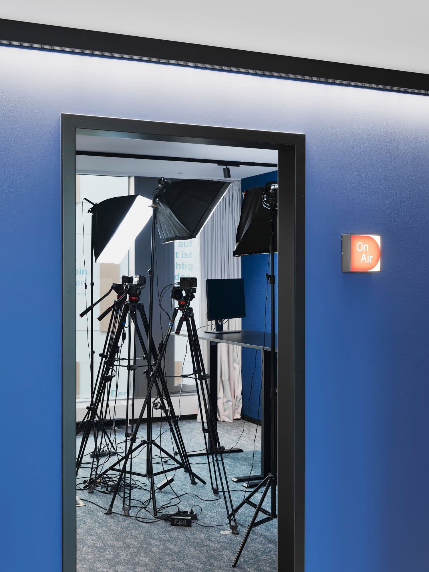 Aufnahmestudio mit Kamerastativen, Studiolicht und leuchtendem On-Air-Schild an der blauen Außenwand im TÜV Verband Berlin